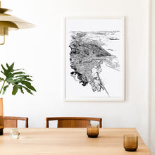 Load image into Gallery viewer, A black and white illustrated map of Nelson laid out on white paper within a white frame, on a white wall above a table setting.