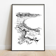 Load image into Gallery viewer, A black and white illustrated print of Kaikōura laid out on white paper, framed in a black frame, leaning on a white wall and wooden flooring.