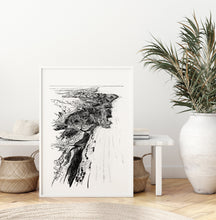 Load image into Gallery viewer, A black and white illustrated map of Piha laid out on white paper within a white frame, leaning against a white bench seat and wooden flooring.