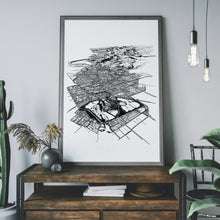 Load image into Gallery viewer, A black and white illustrated print of Christchurch City laid out on white paper within a grey frame leaning against a lighter grey wall and on a dark modern wooden console with black metal detailing.