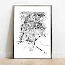 Load image into Gallery viewer, A black and white illustrated print of Hanmer Springs laid out on white paper, framed in a black frame, leaning on a white wall and wooden flooring.